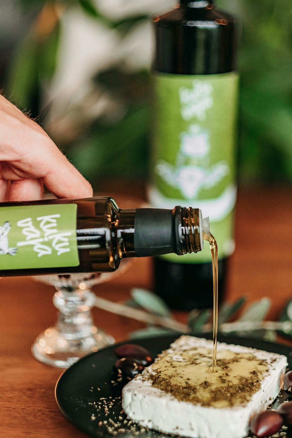 Se vierte aceite de oliva sobre queso con aceitunas.