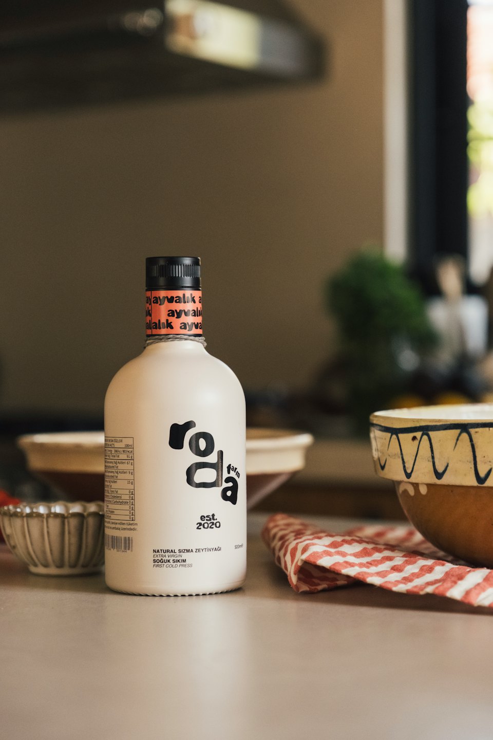 Una botella de aceite de oliva Roda Farm está sobre la encimera de una cocina.
