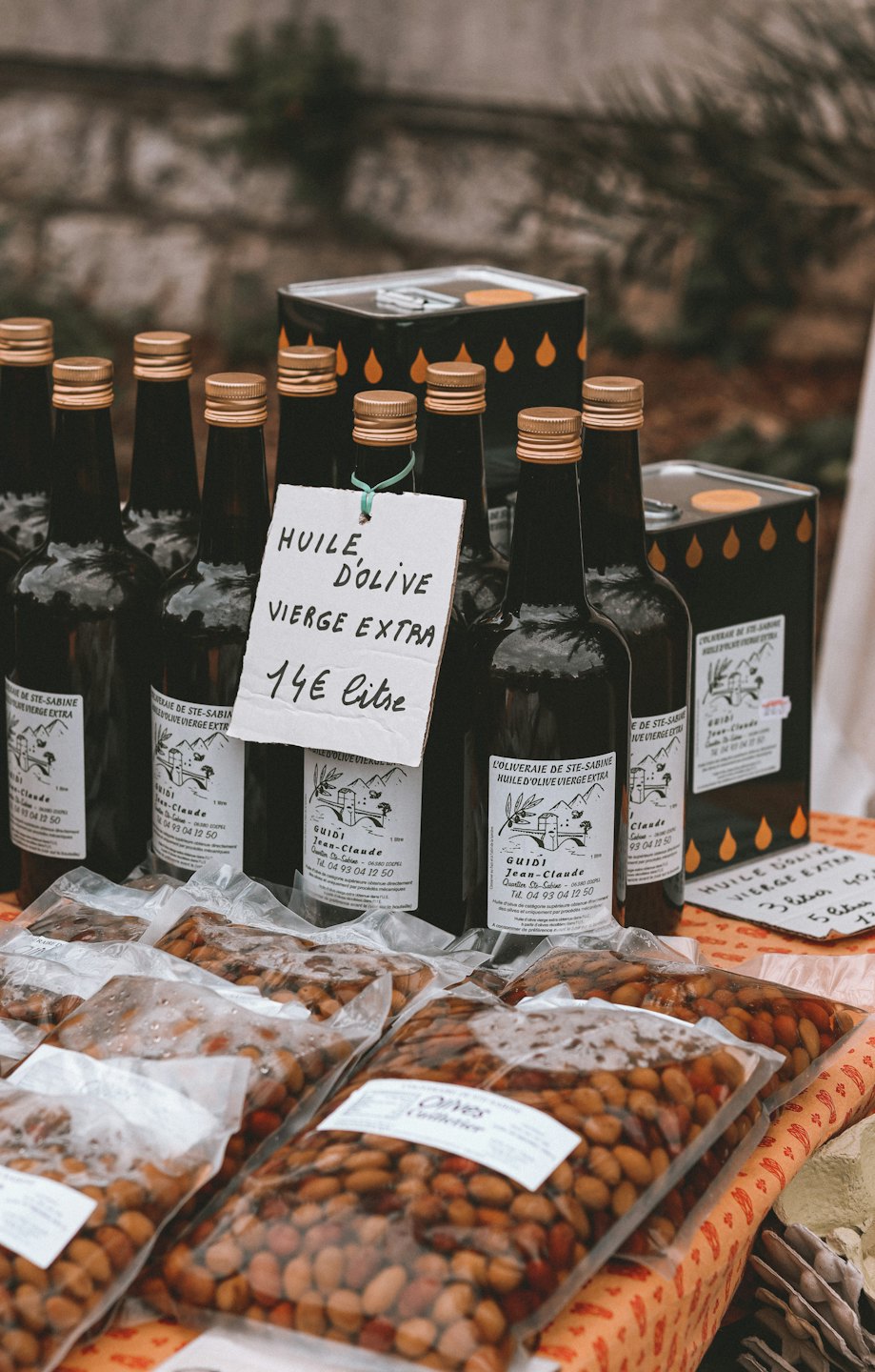 Botellas de aceite de oliva y aceitunas a la venta en un puesto del mercado.