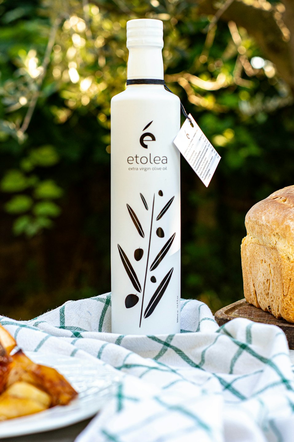 Botella de aceite de oliva etolea y pan sobre un mantel a cuadros.