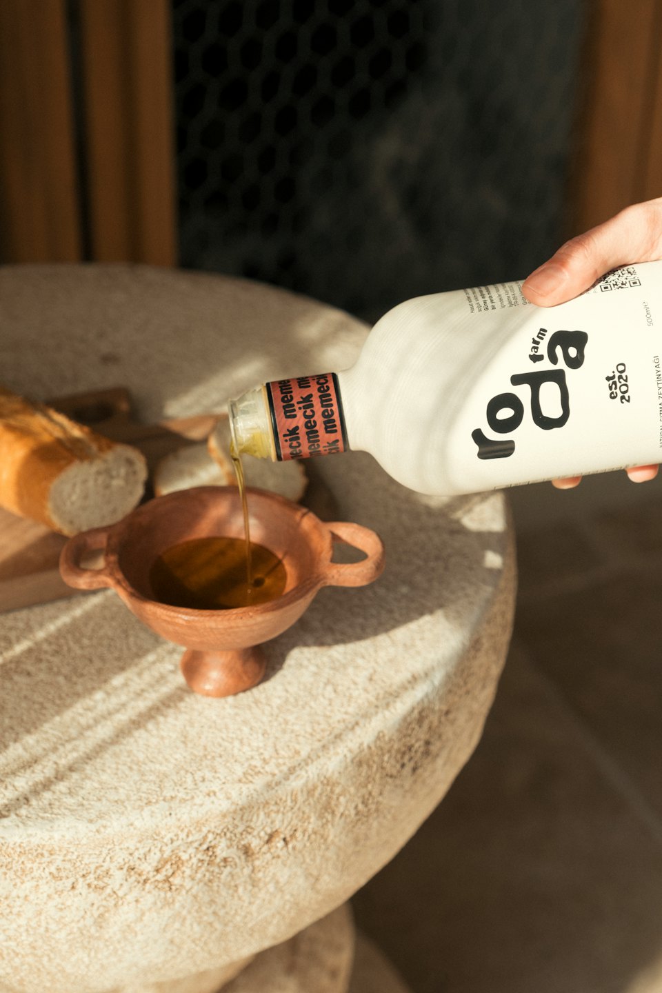 Una mano vierte aceite de oliva de una botella en un cuenco.
